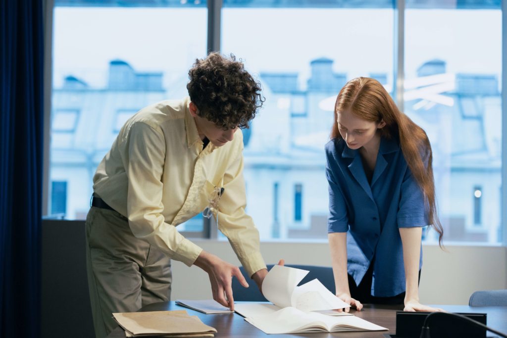 A man and woman looking over documents on a table in an office. Broker dealer audit. Ernst Wintter & Associates LLP.